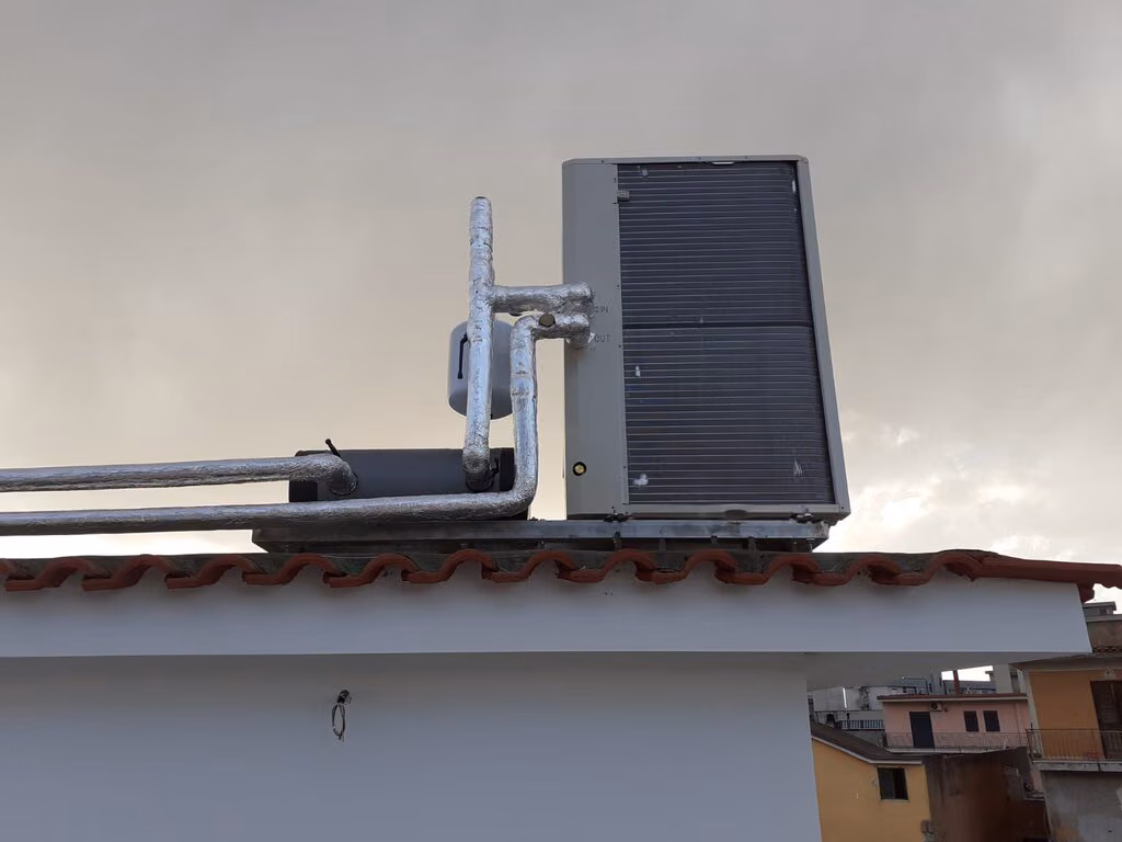 Unità esterna di climatizzatore su un edificio con tetto rosso