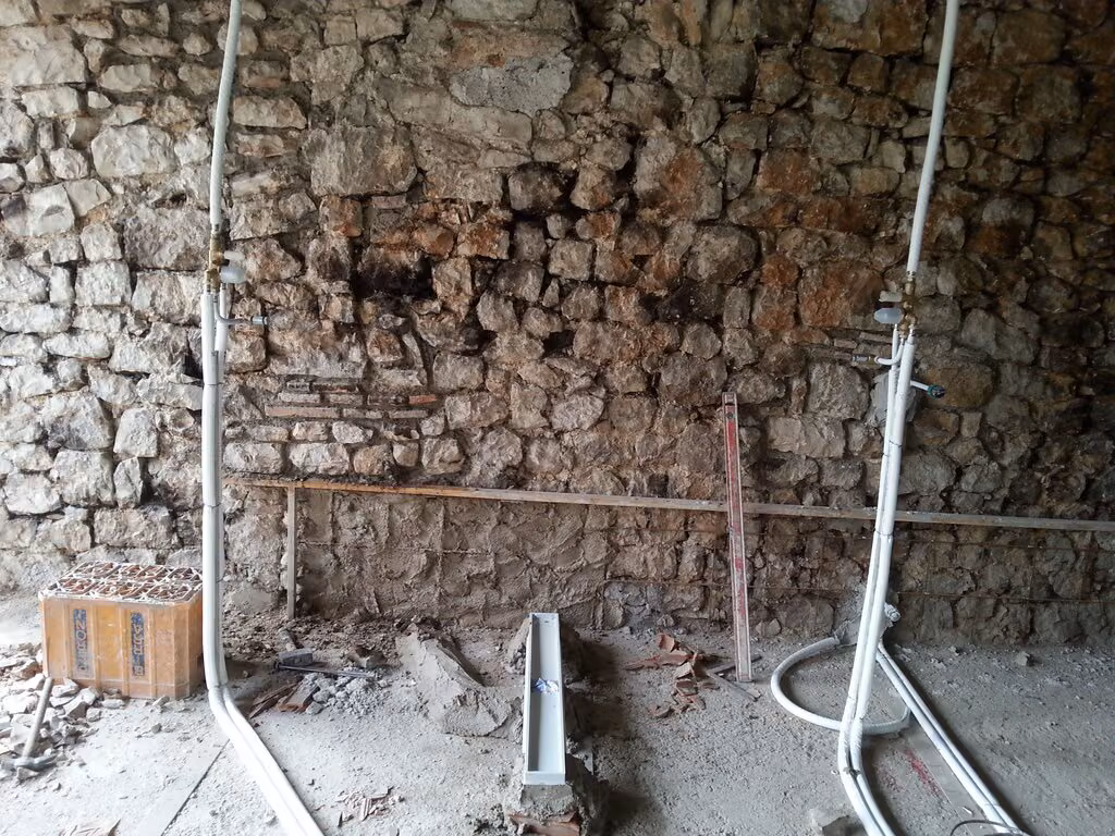 Tubazioni e rubinetti su una parete in pietra, all'esterno